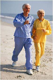 Two people walking on the beach wearing yellow and blue.