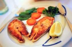 A plate of food with fish and vegetables on it.