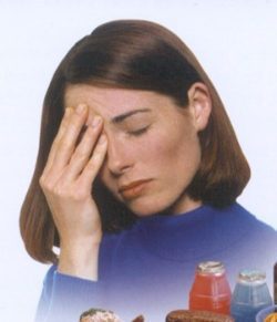 A woman holding her head in front of a bottle.