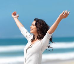 A woman with her arms in the air on the beach