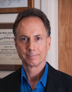 A man in a suit and tie standing next to a wall.