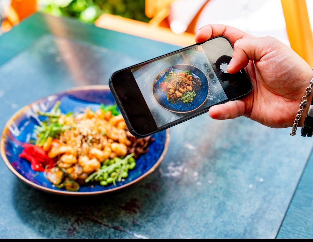 Person photographing colorful, healthy meal on table.